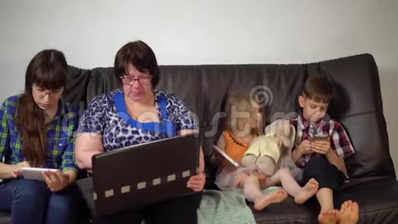 一家人坐在沙发上使用数字设备视频的预览图