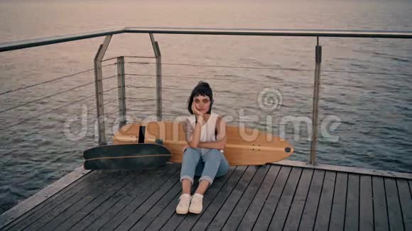 年轻漂亮的女孩码头上有长板视频的预览图