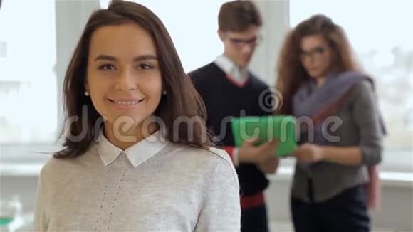 男人和女人看着办公室里微笑的女孩后面的平板电脑视频的预览图