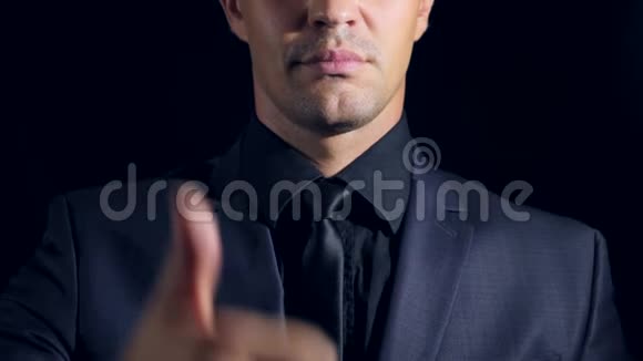 黑色背景下穿黑色衣服的男人的超级特写4k慢动作男人竖起大拇指超级标志视频的预览图