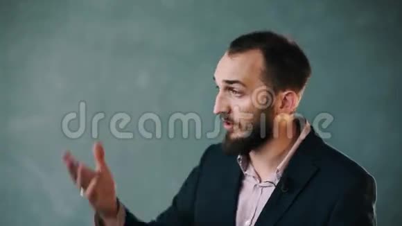 一个穿着夹克和条纹衬衫的大胡子男人说话时活跃地做手势视频的预览图