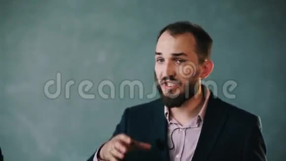 穿着夹克和条纹衬衫的大胡子男人在隔离墙上讲话时打手势视频的预览图