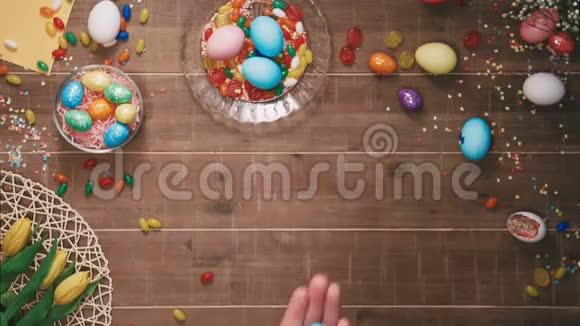 手拿复活节彩蛋摆在摆满复活节彩蛋的桌子前顶部视图视频的预览图