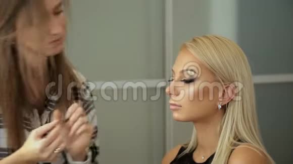 美容院化妆师把睫毛贴到金发眼睛上视频的预览图