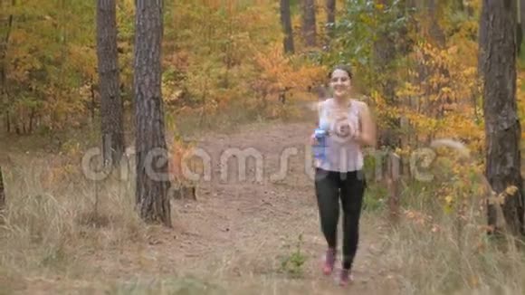 4k片年轻女子在森林里慢跑和饮水视频的预览图