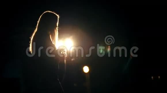 一位女士在明亮的灯笼剪影前用麦克风唱歌视频的预览图