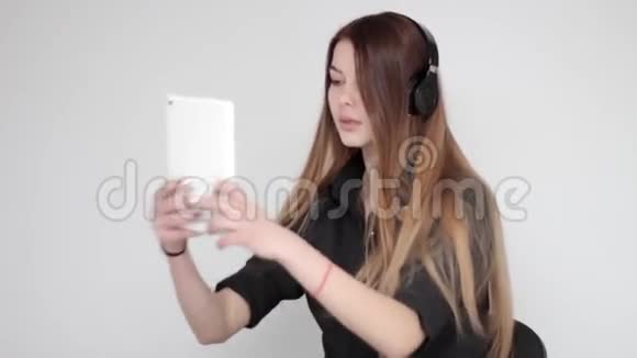年轻漂亮的女士戴着耳机听音乐用平板电脑拍照视频的预览图