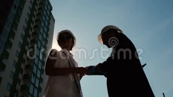 戴着头盔的男人和女人在建筑附近说话视频的预览图