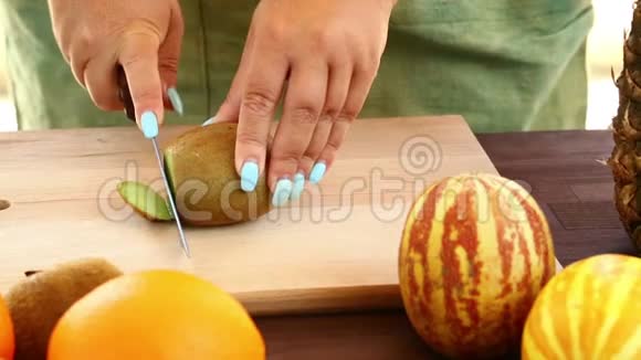 素食一个女人拿着一把猕猴桃开刀它在一个切割板上视频的预览图