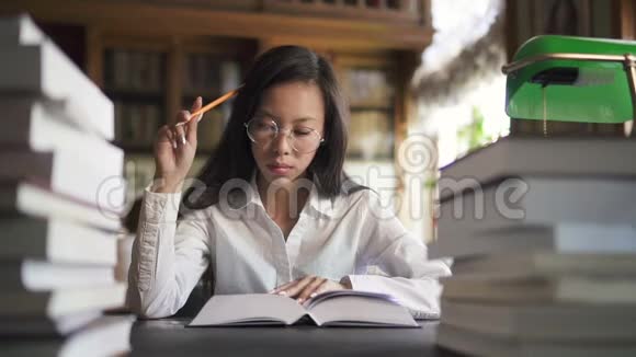 漂亮的女学生正坐在大学图书馆的桌子旁看书视频的预览图