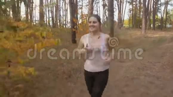 在森林里慢跑时美丽的年轻女子在听音乐视频的预览图