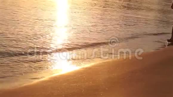 年轻人在海边散步看日落和海浪一个人在日落时沿着海滩散步一片大海视频的预览图