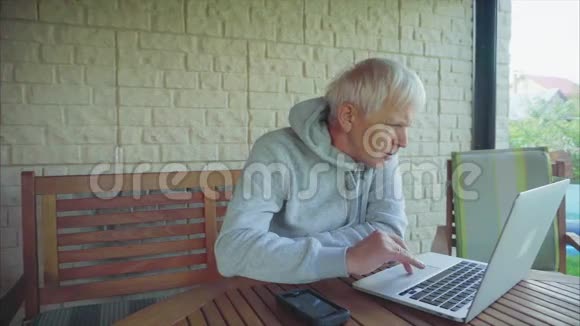 老人坐在门廊外上网视频的预览图