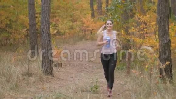 4k片年轻女子在森林里慢跑和饮水视频的预览图