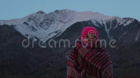 一个女孩的肖像裹在山脚下的格子毯子里视频的预览图