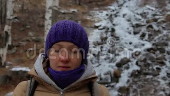 年轻女子在冬天的森林里的一条山涧附近冥想特写视频的预览图