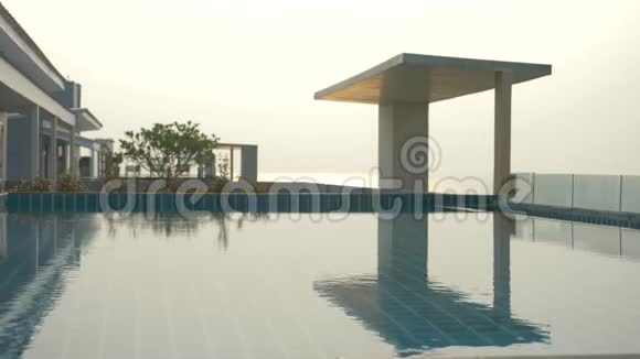 房子屋顶上有一个豪华的游泳池有海景在日落的时候4k慢动作水上有太阳眩光视频的预览图