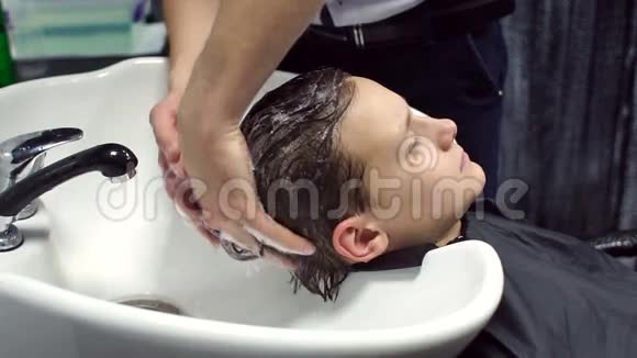男理发师洗一个男孩的头发视频的预览图