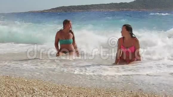慢莫两个美丽的女孩享受阳光和大海躺在海岸上视频的预览图