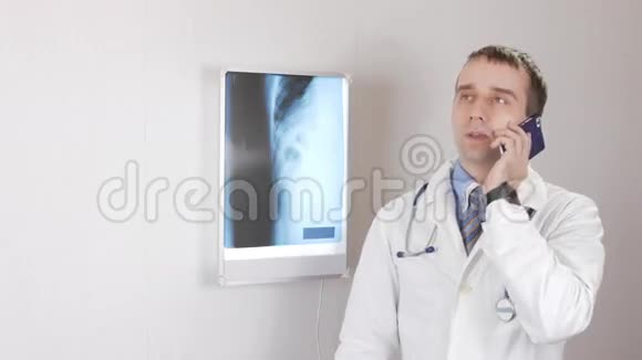一位年轻的男医生通过电话咨询白色墙壁和一个内窥镜背景是肋骨和肋骨视频的预览图
