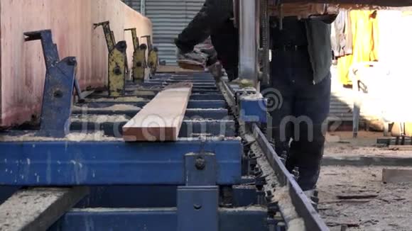 专门从事切割大型原木的机器和搬运切割的钢轨上的木板推动机构的工作视频的预览图