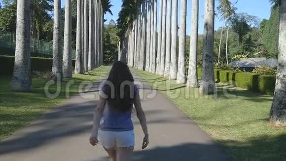 年轻美丽的女人慢跑和旋转的异国公园和乐趣快乐女孩在热带公园跑步视频的预览图