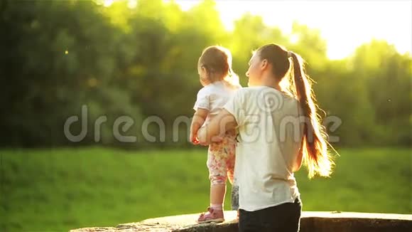 快乐的母亲和孩子在阳光明媚的大自然中一起享受妈妈和女儿站在女儿墙上视频的预览图
