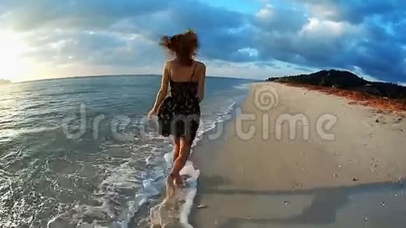 日落时分在海滩上奔跑的年轻女士视频的预览图
