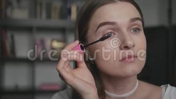 迷人的女孩非常小心地为眼睫毛涂上墨水使自己晚上化妆动作缓慢视频的预览图