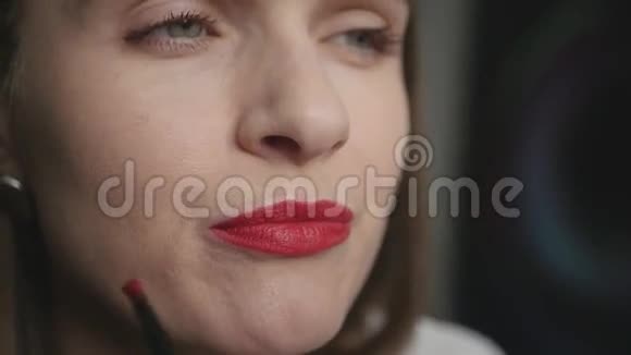 漂亮迷人的女孩用刷子小心地涂上红色口红动作缓慢视频的预览图