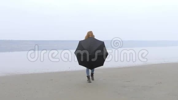 女孩在雨伞后走向沙滩上的摄像机笑了视频的预览图