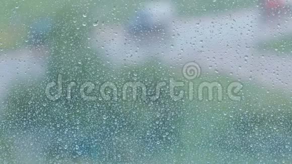 雨滴沿着窗户的特写从潮湿的窗户看城市和道路模糊视频的预览图