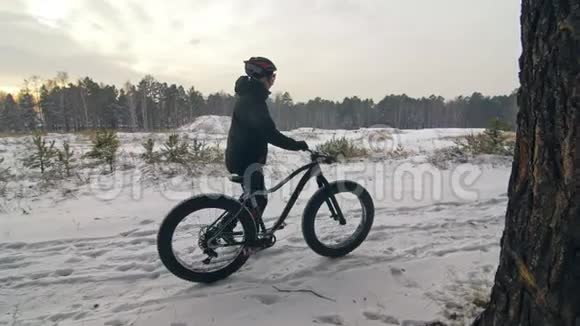 专业极限运动员在户外骑着胖自行车散步骑自行车的人在冬天的雪林里散步哥们走视频的预览图