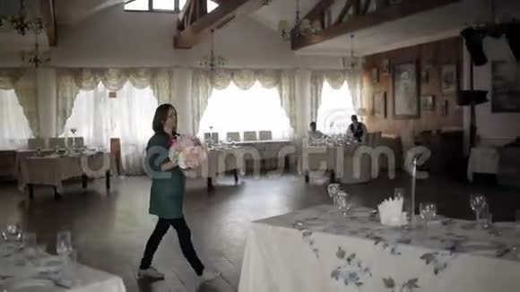 年轻女子在餐桌上装饰鲜花在高玻璃花瓶中装饰鲜花节日餐桌装饰婚礼视频的预览图