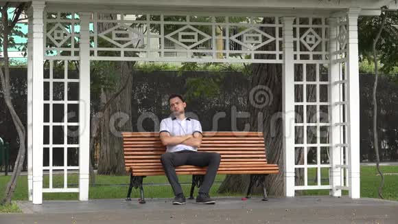 孤独的人坐在公园的长凳上视频的预览图