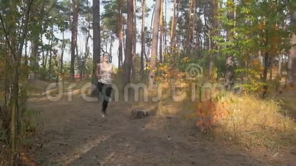 清晨微笑的年轻女子在森林小径上缓慢地奔跑视频的预览图