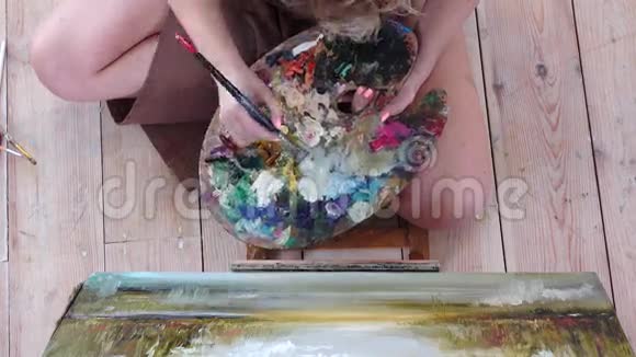 女孩艺术家画坐在地板上的画顶部视图视频的预览图