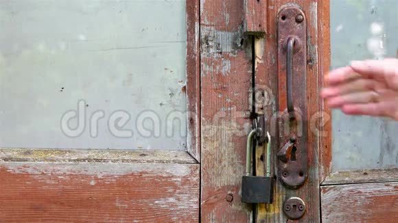 一只人手拿着一扇红棕色的烂门的门把手视频的预览图