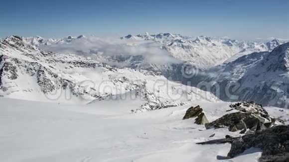 阳光明媚的一天在冬天的雪山阿尔卑斯山的云层之上时间流逝多莉飞过岩石和雪流视频的预览图