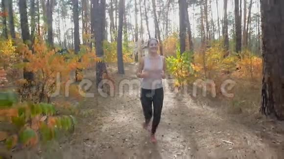 日落时分幸福微笑的女人在森林小径上缓慢地奔跑视频的预览图