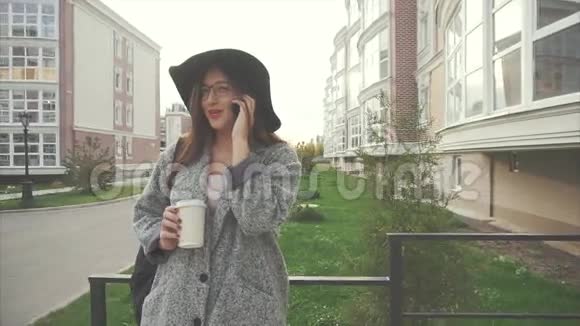 漂亮时尚戴着帽子和眼镜的商务女性在户外打电话视频的预览图