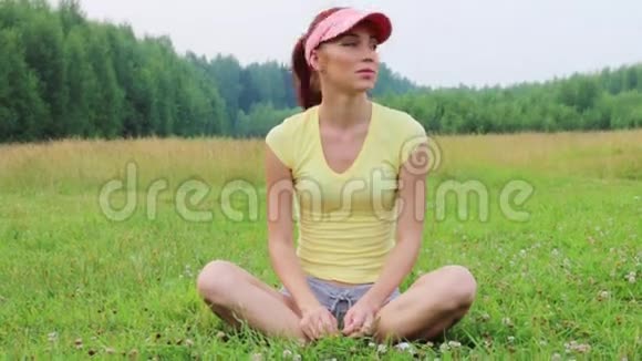 美丽的女孩坐在绿色的草地上在夏天的夜晚欢乐视频的预览图