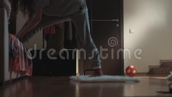 客厅里年轻的黑发女孩在地毯上滑倒在地板上伸展视频的预览图