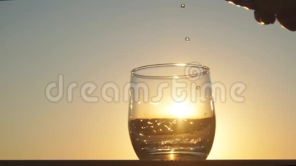 干净新鲜的水在夕阳下倒入一杯慢动作视频的预览图