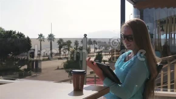 一个漂亮的女人在夏天用平板电脑喝咖啡视频的预览图