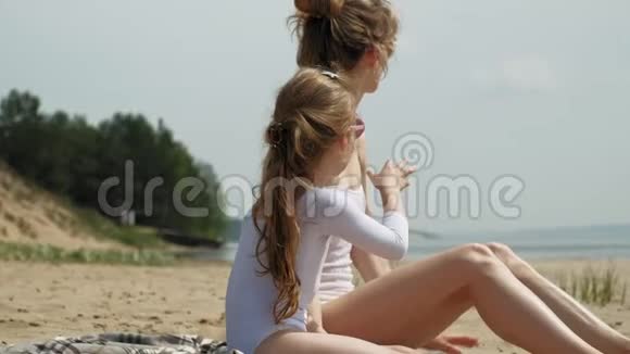 妈妈和女儿正在海滩上晒日光浴夏日晴天视频的预览图