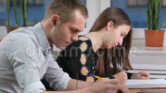 男学生坐在讲座中戴着耳机听音乐他没有听见坐在旁边的女人视频的预览图