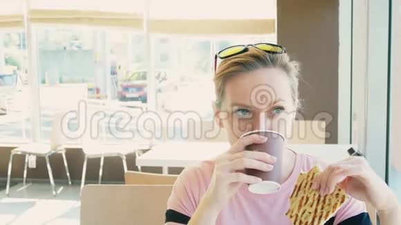 漂亮的女人吃三明治在快餐店喝咖啡快餐视频的预览图