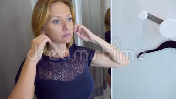女人在服装店购物选择衣服女人在更衣室试穿衣服照镜子4k视频的预览图