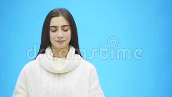 穿着白色衣服的年轻漂亮女孩在这段时间里它站在蓝色的背景上一句爱的话语视频的预览图